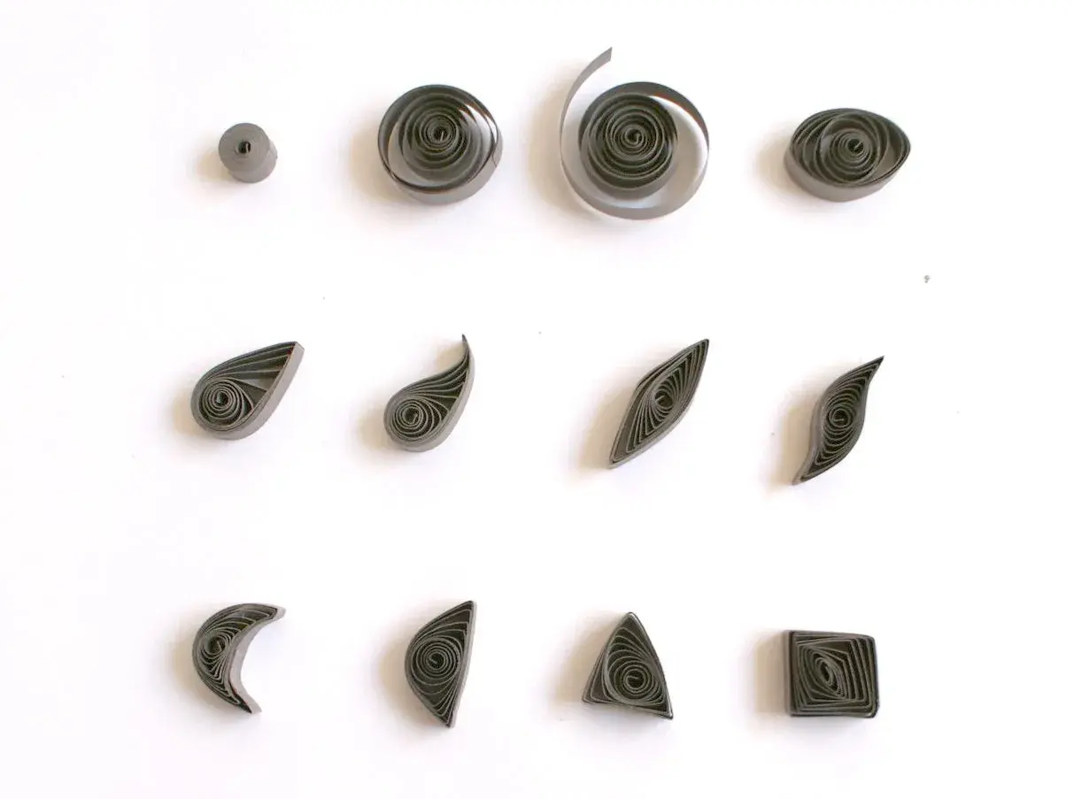 Różne kształty z papieru, pokazujące, quilling co to jest. Kółka, łezki, listki, księżyce, trójkąty i kwadraty.