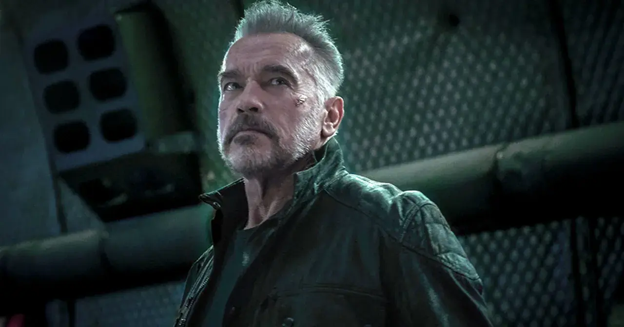Arnold Schwarzenegger jako T-800 w filmach Jamesa Camerona. Z blizną na policzku, w skórzanej kurtce, patrzy w górę.
