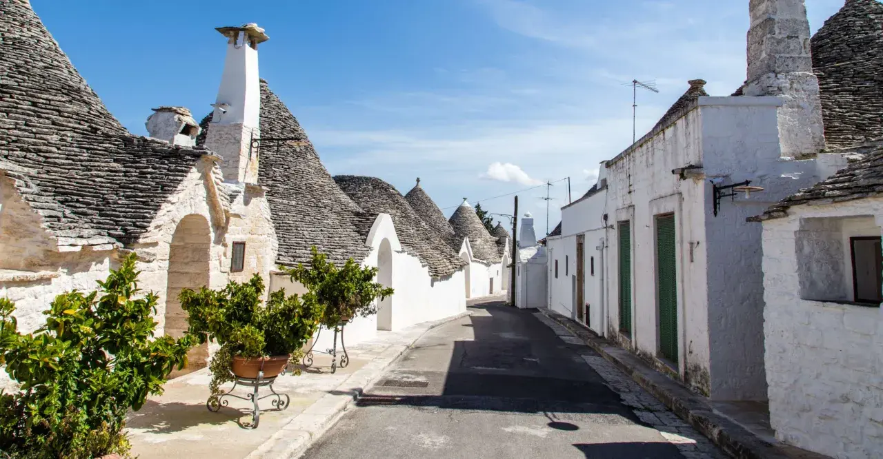 Un vicolo tra i trulli, con i loro tetti conici in pietra, mostra cosa sono i trulli, un'architettura unica della Puglia.