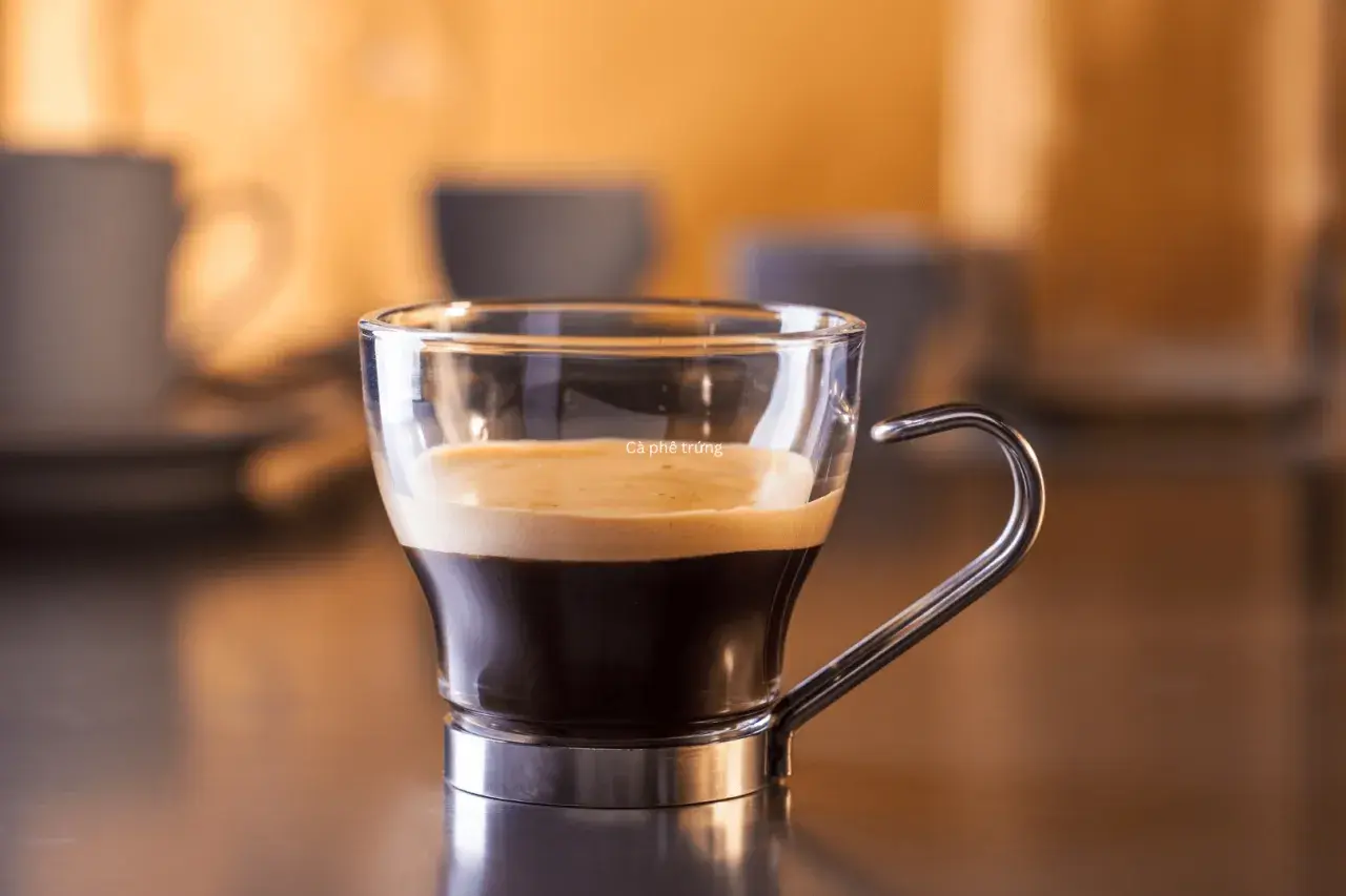 Kawa ristretto w szklanej filiżance z metalowym uchem. Kremowa pianka na ciemnym espresso.