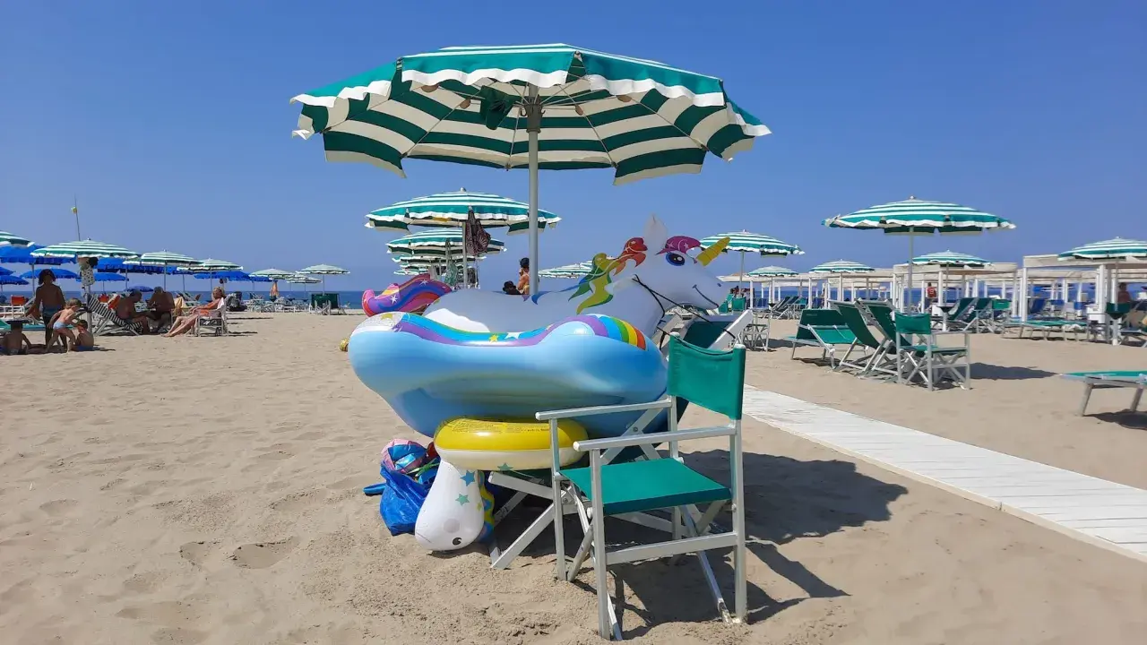 Spiaggia di Viareggio con gonfiabili a forma di unicorno e arcobaleno, pronti per i bambini.