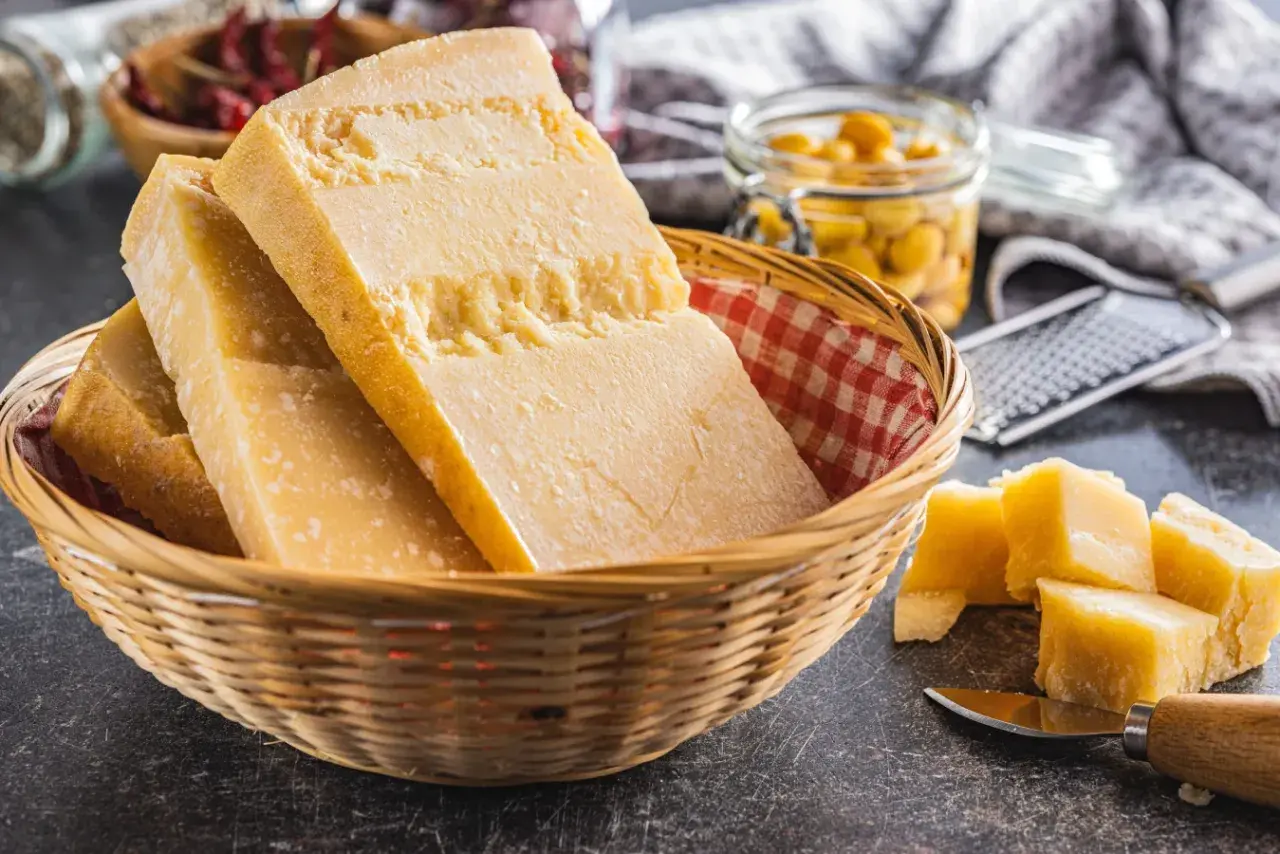 Kawałki sera Grana Padano w koszyku, obok pokrojone w kostkę. To jest właśnie to, co to jest Grana Padano.