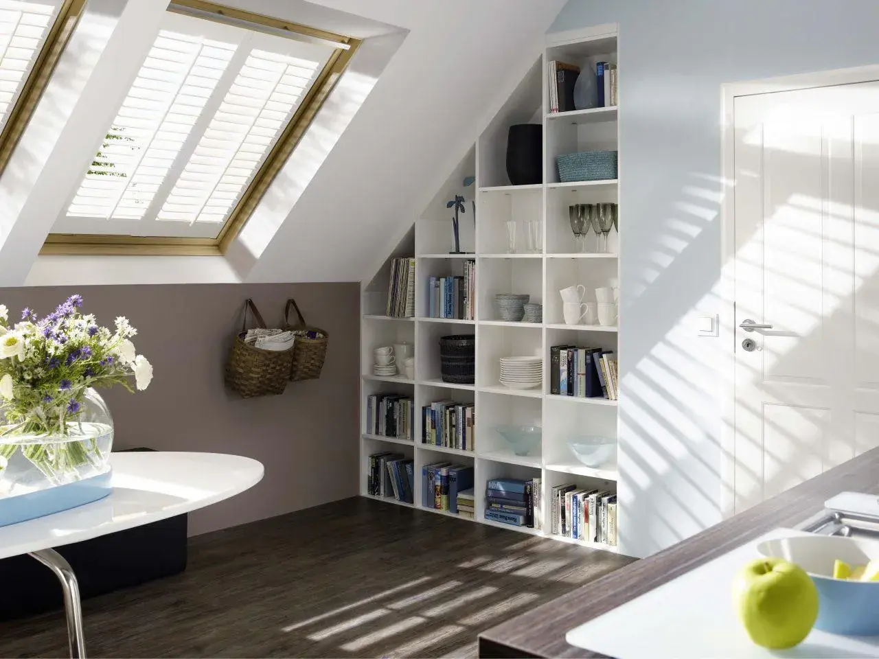 Una libreria in mansarda, piena di libri e oggetti decorativi, si integra perfettamente con l'ambiente.