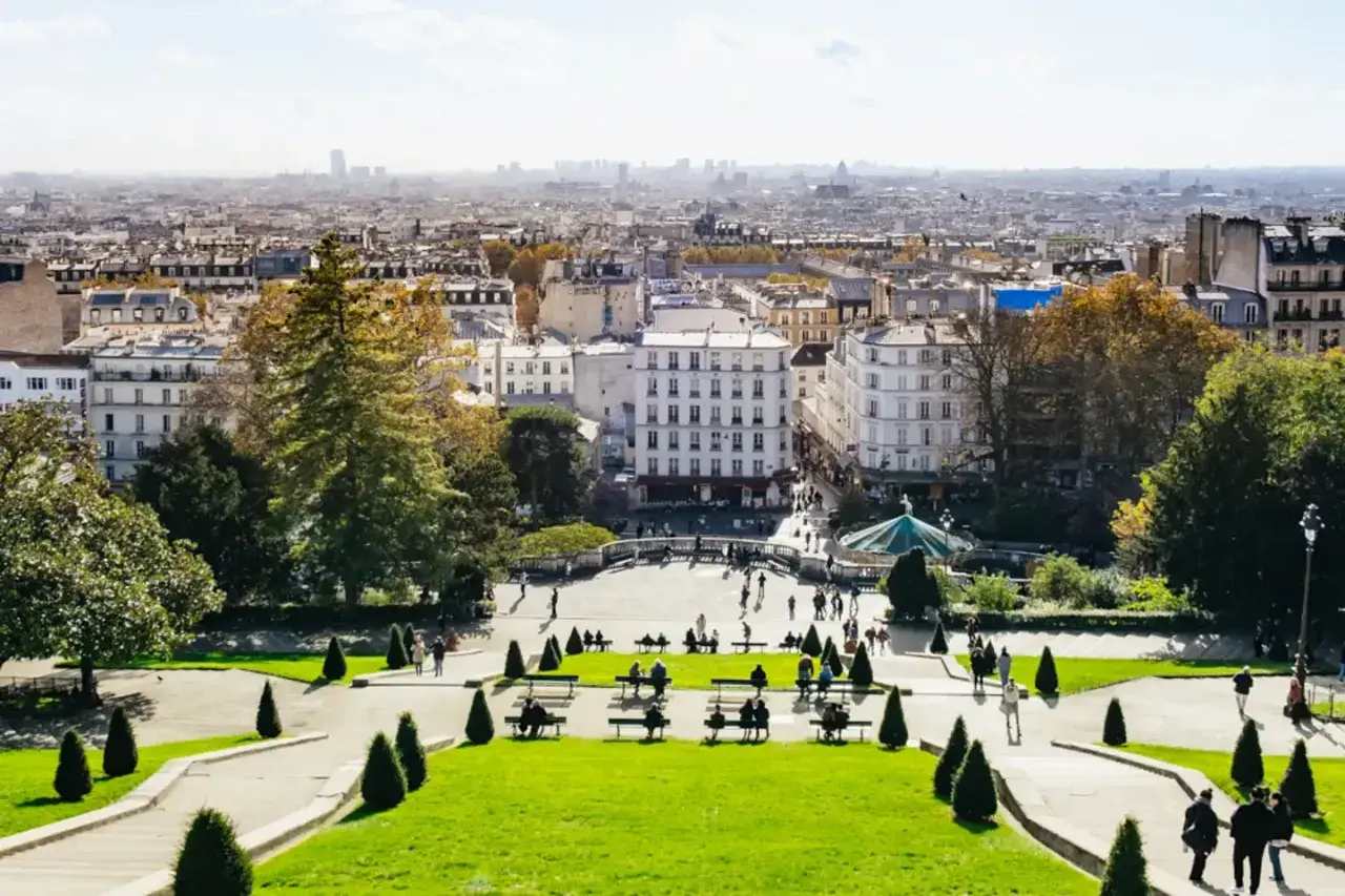 Blick über das Montmartre Viertel in Paris. Menschen genießen den sonnigen Tag im Park mit Blick auf die Stadt.
