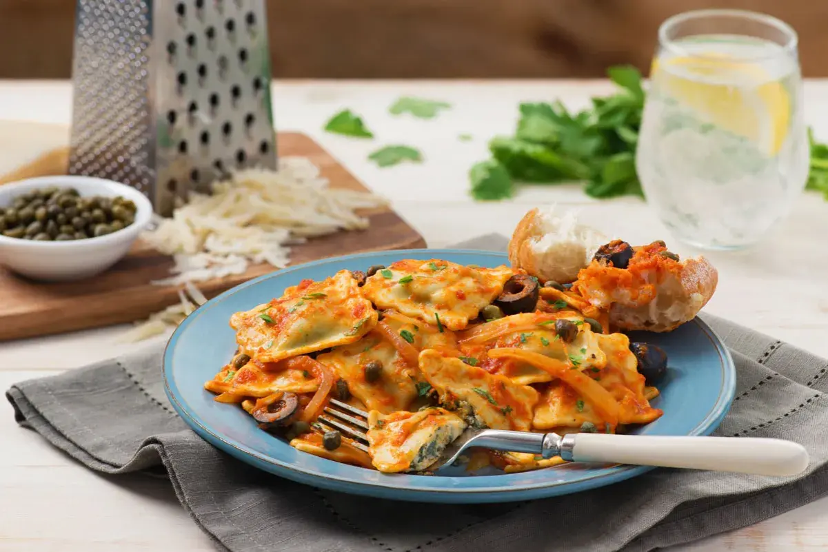 Délicieux ravioli ricotta épinard, une recette italienne savoureuse, servie avec une sauce tomate, des olives et des câpres.