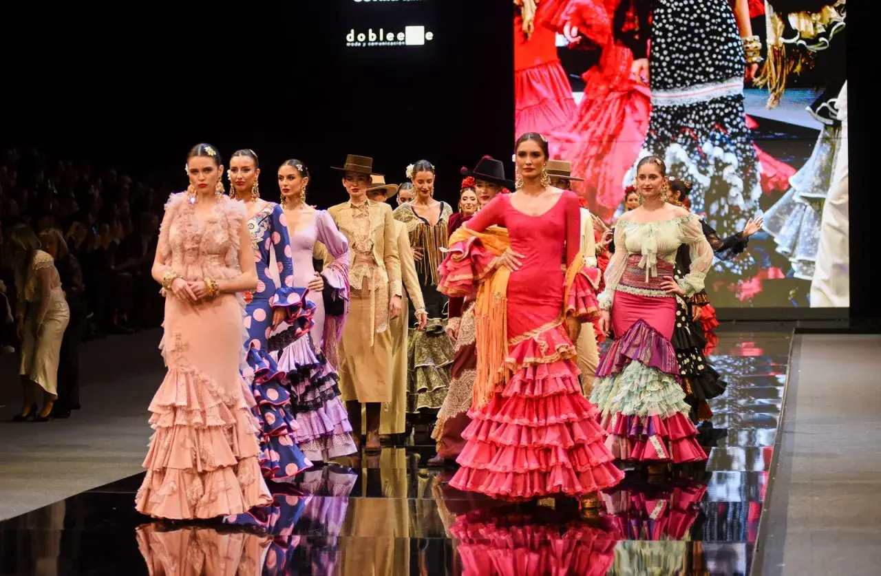Modelos desfilan en la **pasarela SIMOF** con trajes de flamenca vibrantes y volantes.