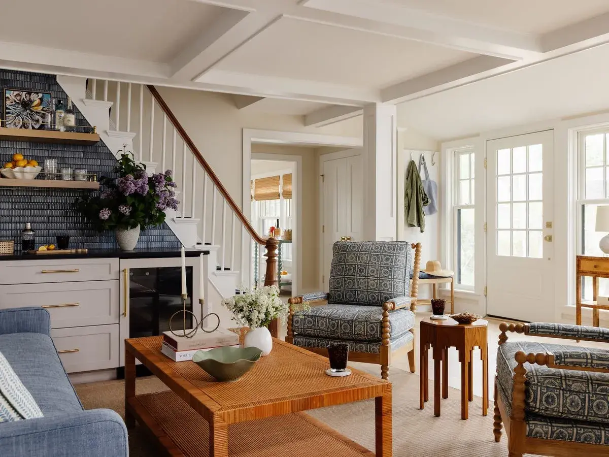 A living room showcasing diverse furniture styles, from a blue sofa and patterned armchairs to a rattan coffee table and a wooden side table.