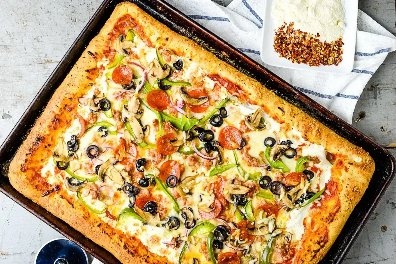 Pyszny przepis na pizzę z serem, pepperoni, pieczarkami, papryką i oliwkami. Idealna na rodzinny obiad.