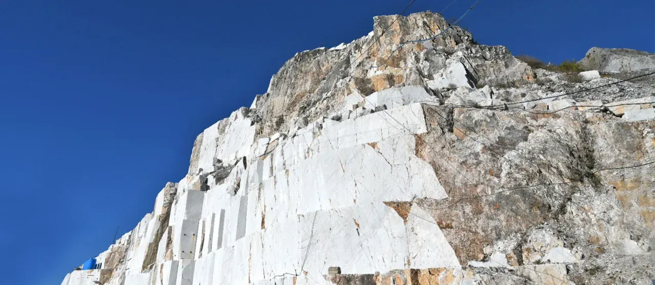 Carrières de marbre blanc à Carrare, Italie, sous un ciel bleu intense. Les blocs taillés révèlent la beauté brute de la roche.