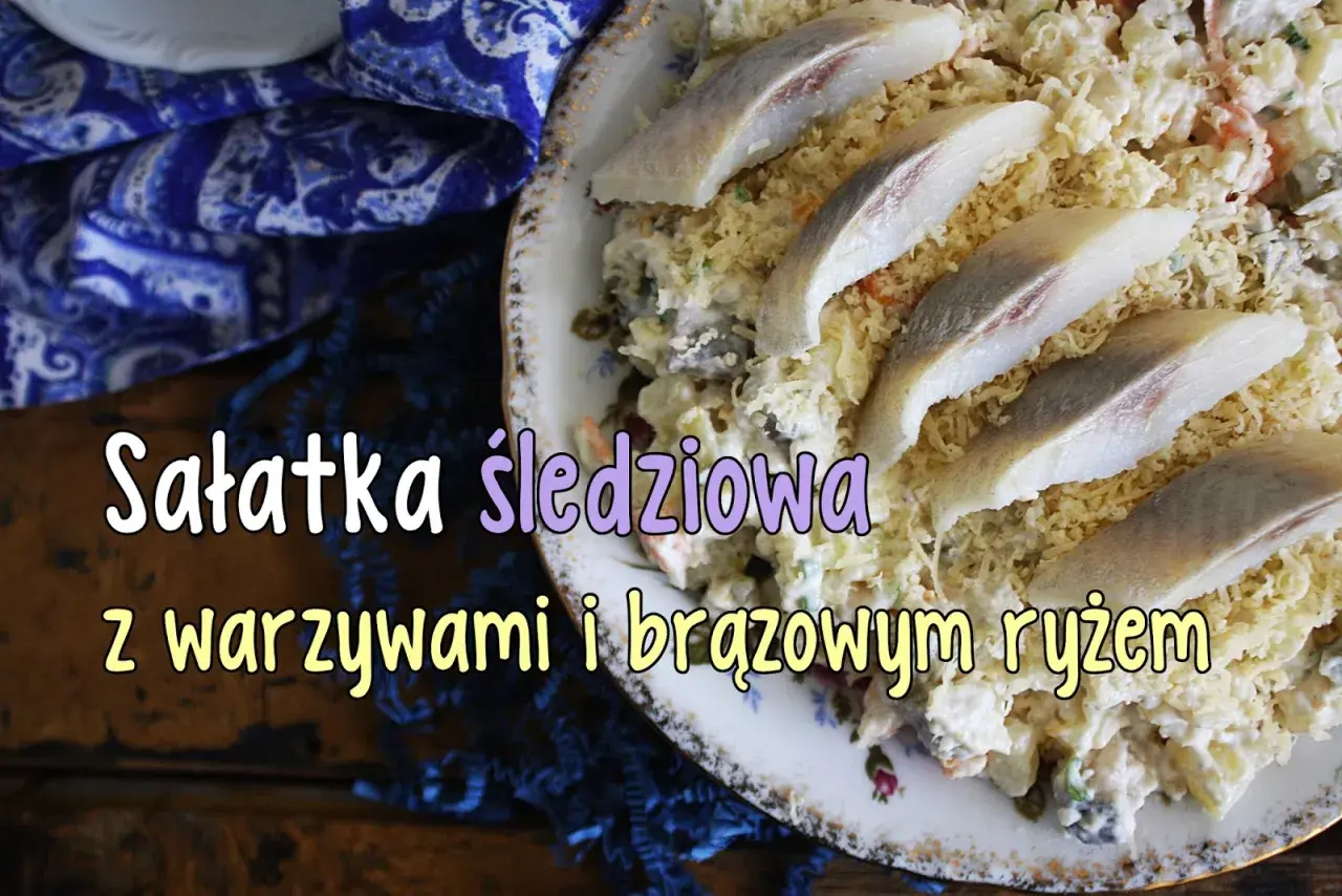 Sałatka śledziowa z warzywami i brązowym ryżem, ozdobiona kawałkami marynowanych śledzi.