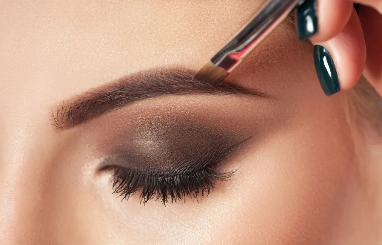 Aplicando el toque final al maquillaje de cejas con un pincel.