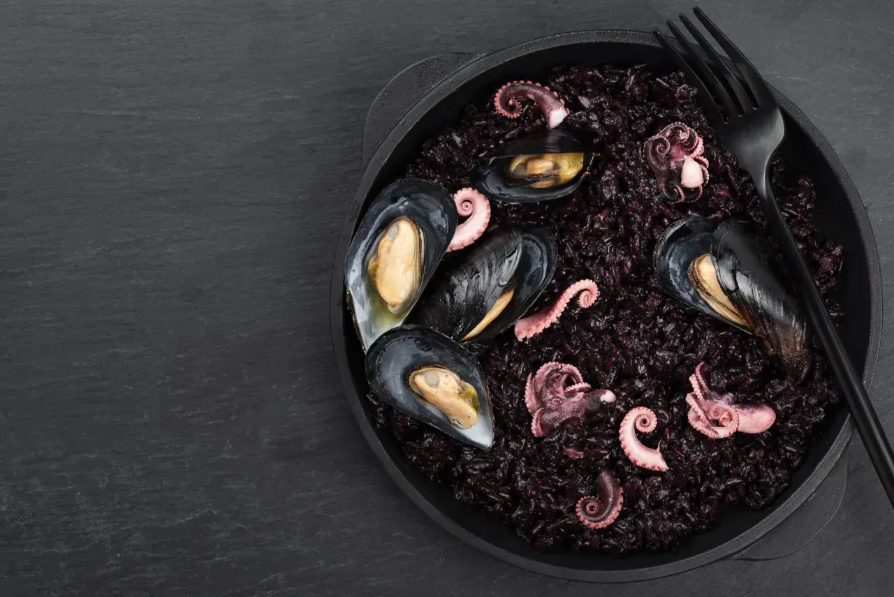 Arroz negro con mejillones y pulpo tierno, un plato de mariscos oscuro y delicioso.