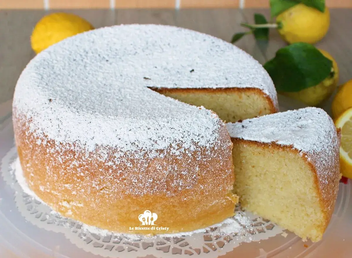 Torta al limone morbidissima e profumatissima benedetta, cosparsa di zucchero a velo. La fetta tagliata rivela la sua sofficità.