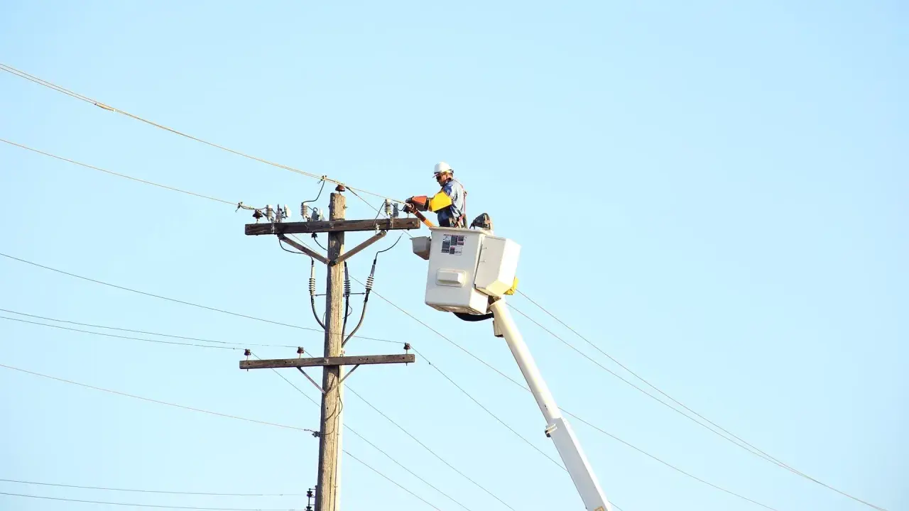 Elektryk wysokich napięć w podnośniku pracuje przy linii energetycznej.