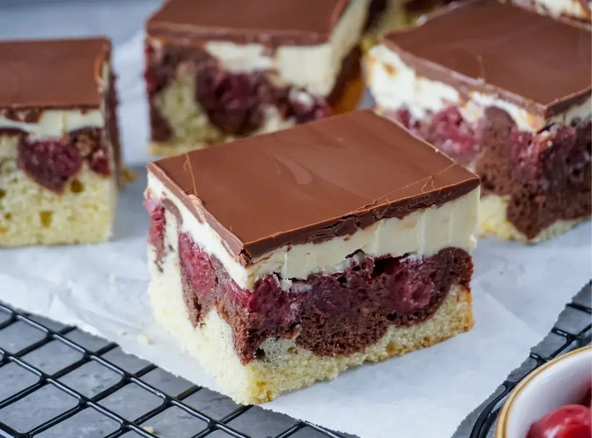 Saftiger Schneewittchenkuchen vom Blech mit Kirschen, Schokoglasur und cremiger Schicht. Ein Genuss für jeden Anlass!