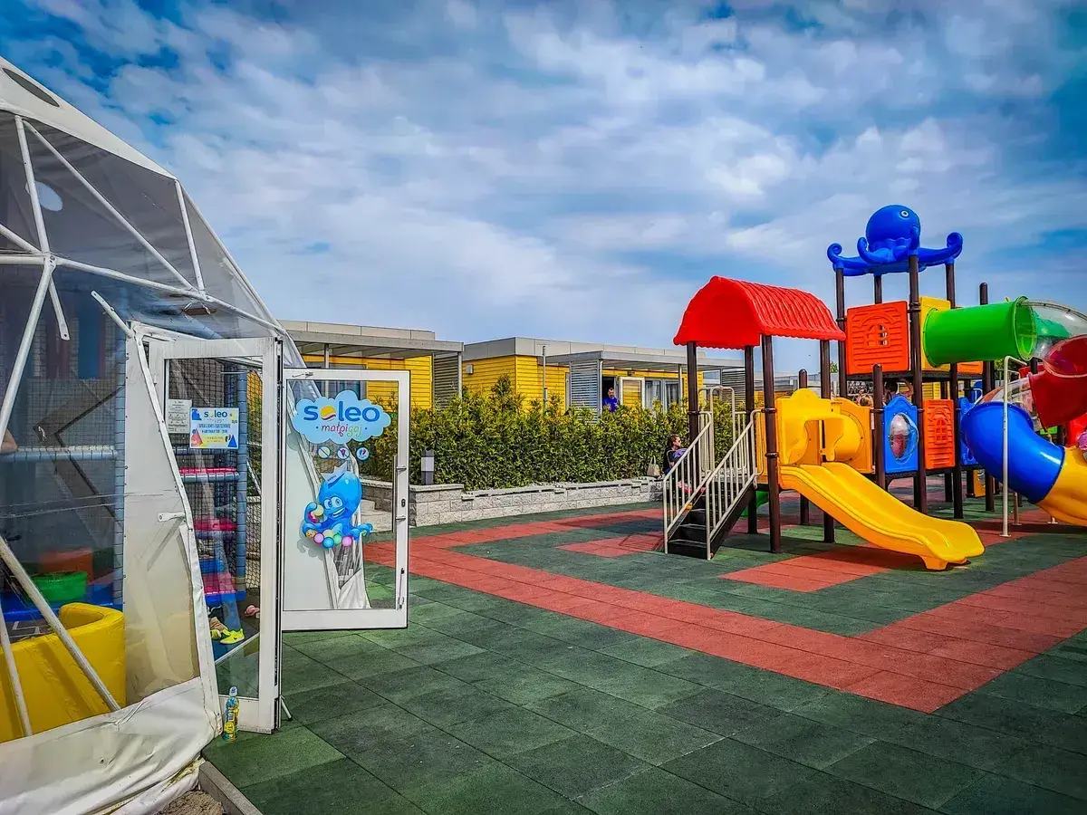 Kolorowy plac zabaw z ośmiornicą i zjeżdżalniami, idealne rewa atrakcje dla dzieci. Obok namiot z atrakcjami dla najmłodszych.