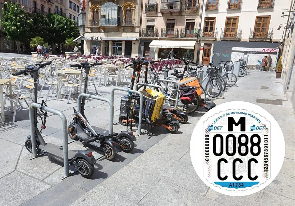 Patinetes eléctricos y bicicletas aparcados en una plaza. Se ve una pegatina de la DGT con la matricula CD.