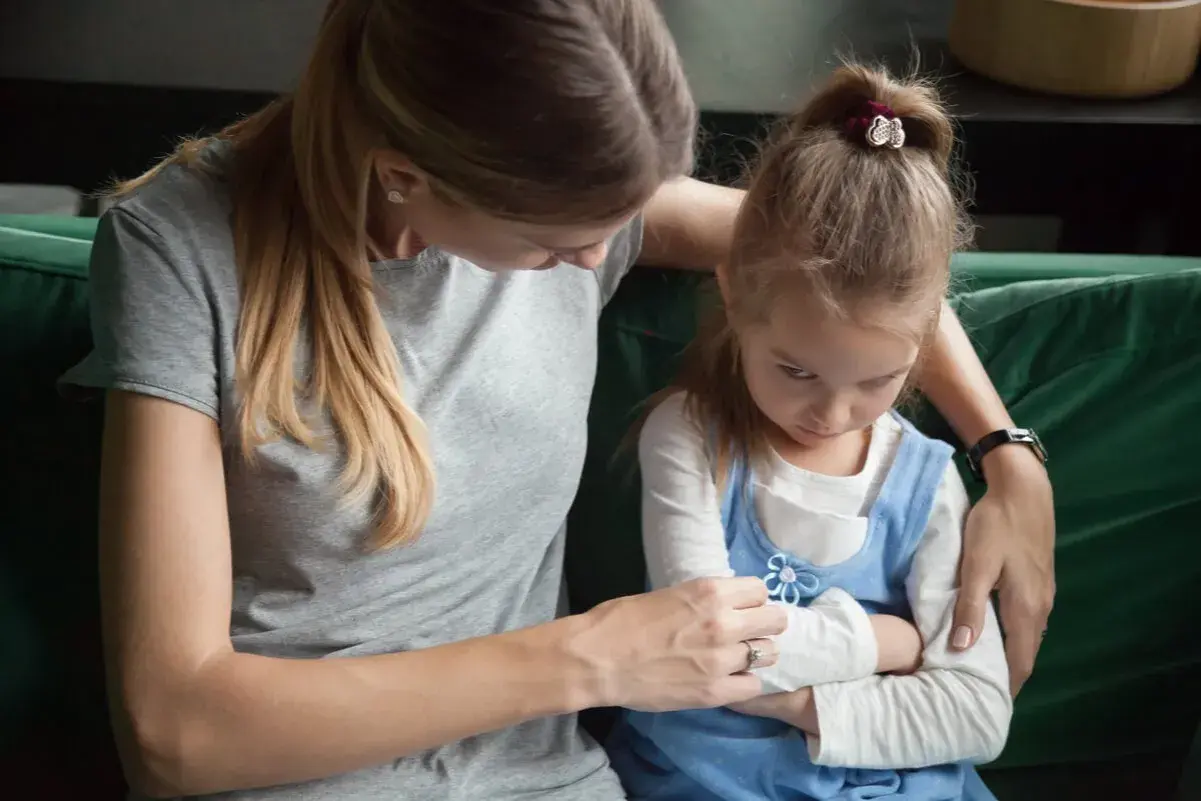 Madre intenta consolar a su hija, que se muestra enfadada y con los brazos cruzados. Un momento difícil cuando un hijo trata mal a su madre.