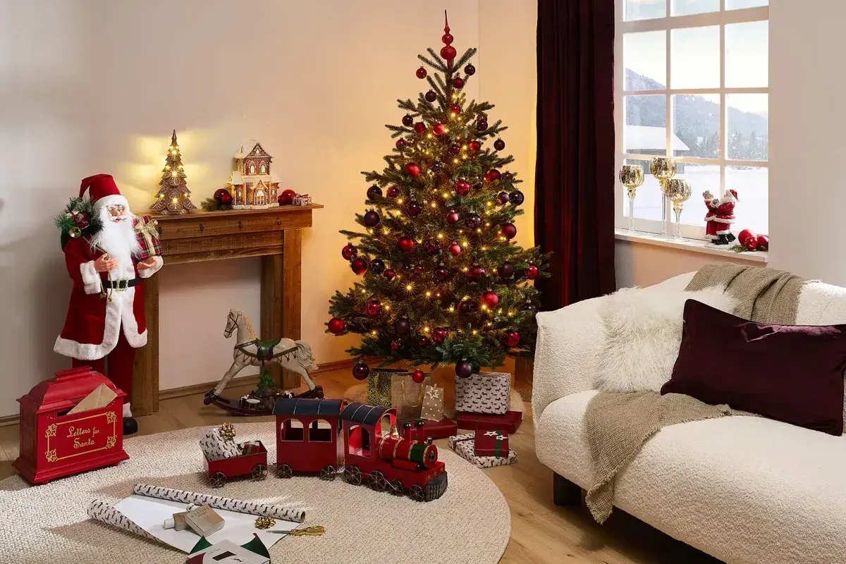 En julgran med röda kulor och ljus ger inspiration till en mysig jul. Tomten, leksakståg och en gungande häst skapar en festlig stämning.