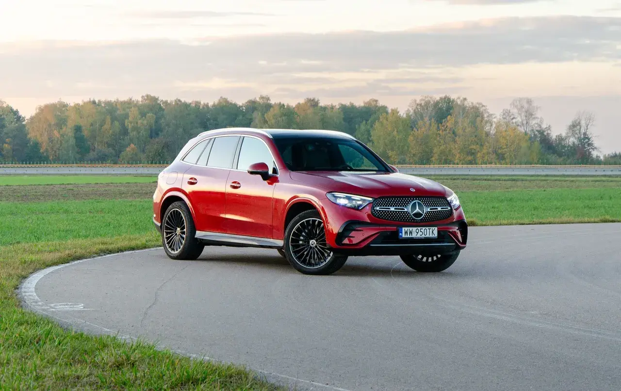 Czerwony Mercedes-Benz GLC 300 na zakręcie toru wyścigowego, z jesiennym lasem w tle.
