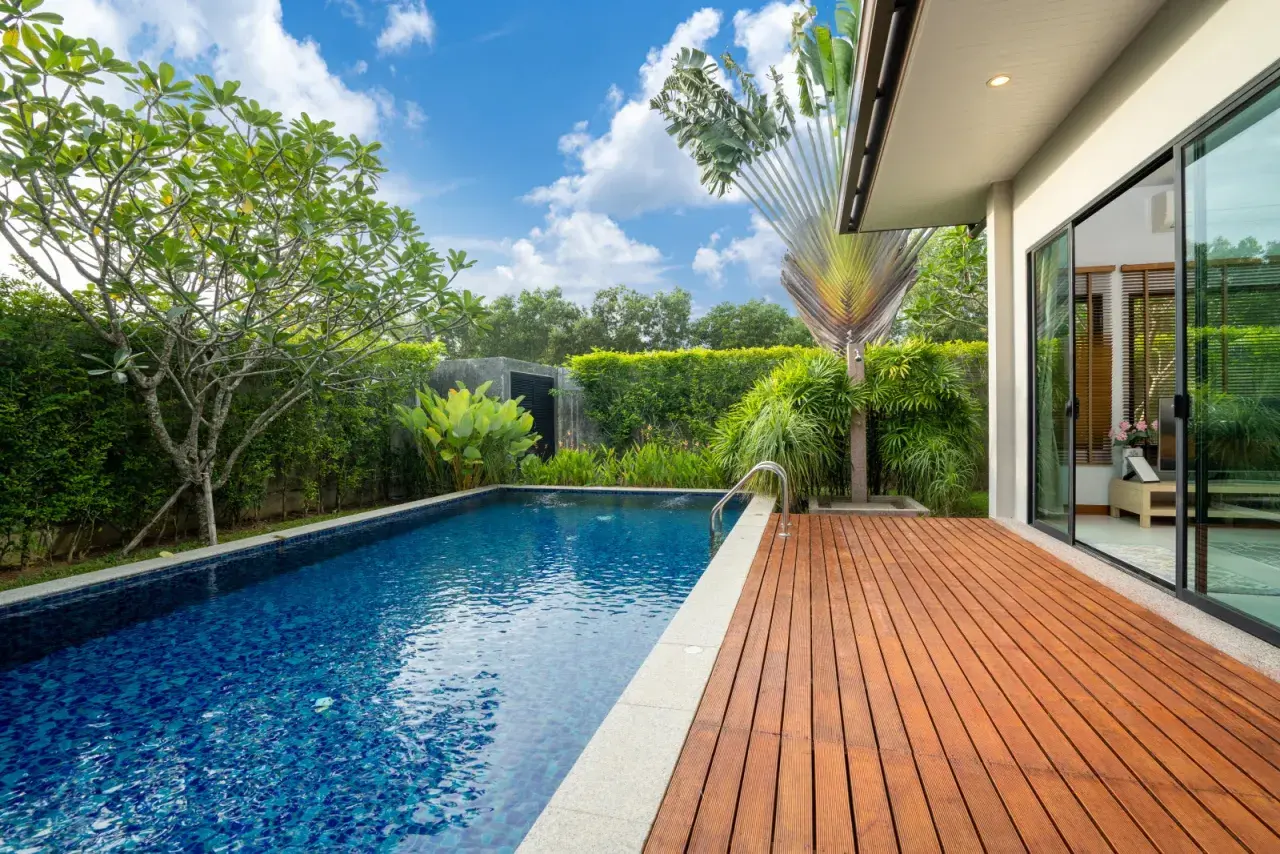 Piscine extérieure avec terrasse en bois, entourée de verdure luxuriante. Un espace de détente qui respecte l'esprit de l'article R.111-19 du code de l'urbanisme.