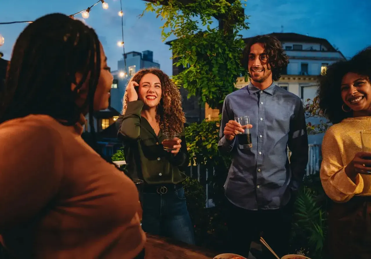 Vänner samlas på en takfest i Berlin, med ljusslingor och stadens silhuett i bakgrunden. En kväll fylld av skratt och goda drinkar, som en liten bit av fakta om Berlin.