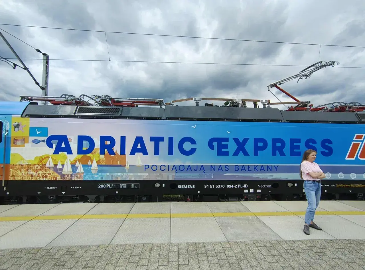 Kobieta na tle lokomotywy "Adriatic Express", która zabierze ją pociągiem do Chorwacji.