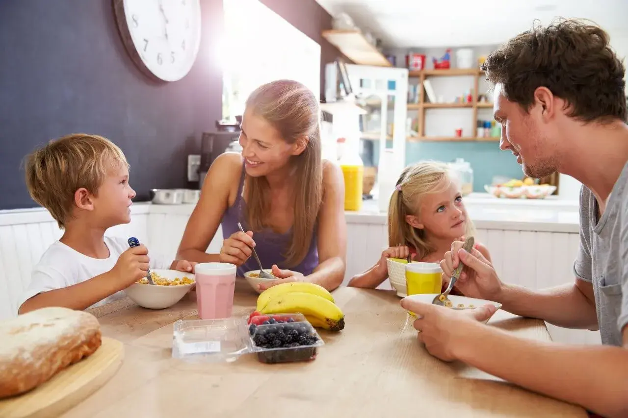 Famiglia felice a colazione, un momento sereno che fa pensare alle detrazioni figli a carico.