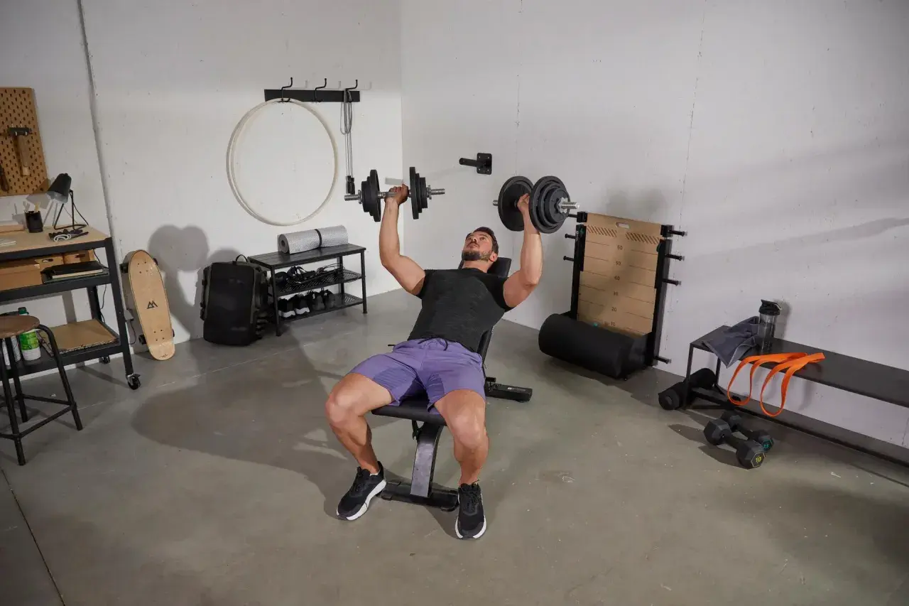 Un homme fait un exercice banc de musculation avec des haltères.