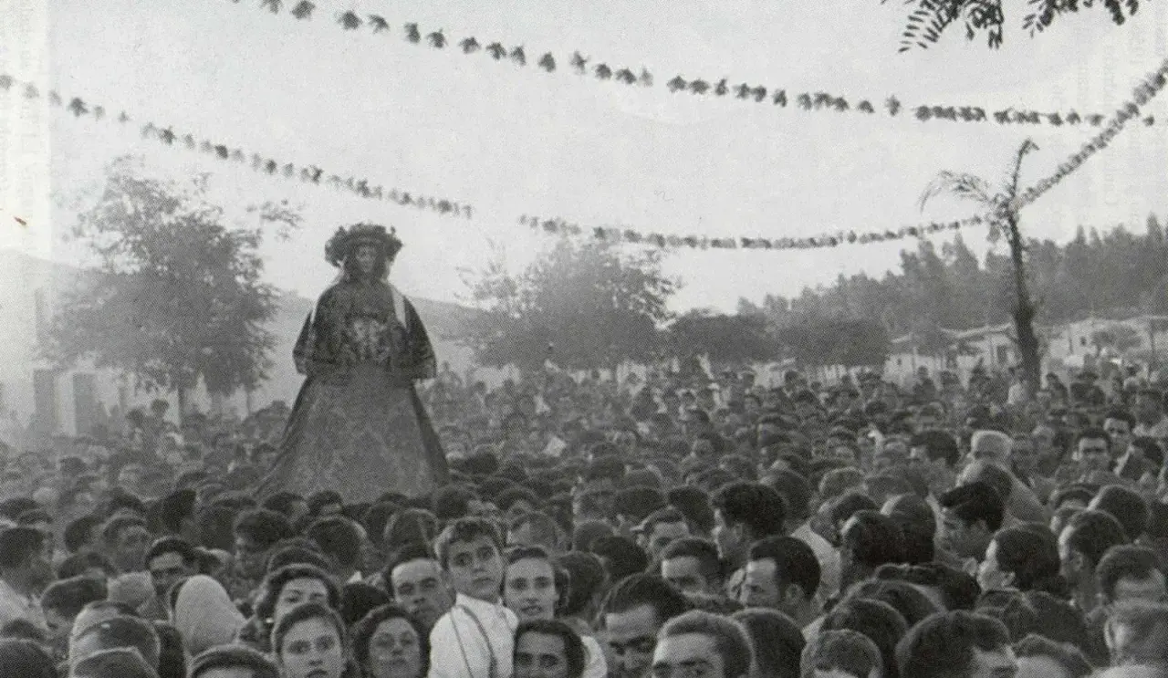 Una figura alta, vestida con traje tradicional, se alza sobre una multitud. Es parte de la **historia del Rocío**, una tradición ancestral.