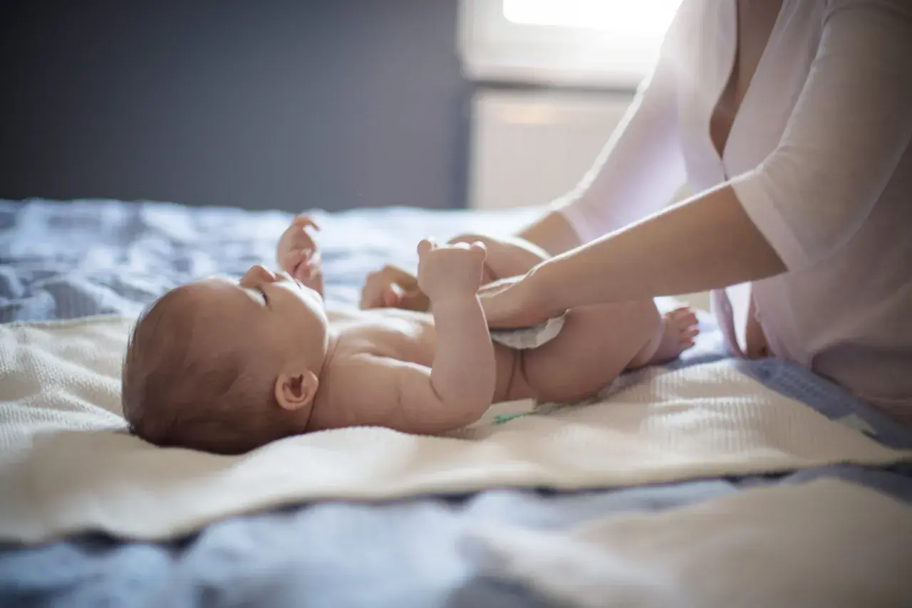 Mama zmienia pieluszkę niemowlaka, który ma biegunkę.