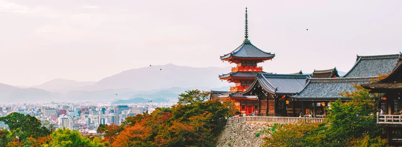 Widok na pagody i tradycyjną architekturę w Kioto, które kiedyś było stolicą Japonii. W tle rozciąga się miejski krajobraz.