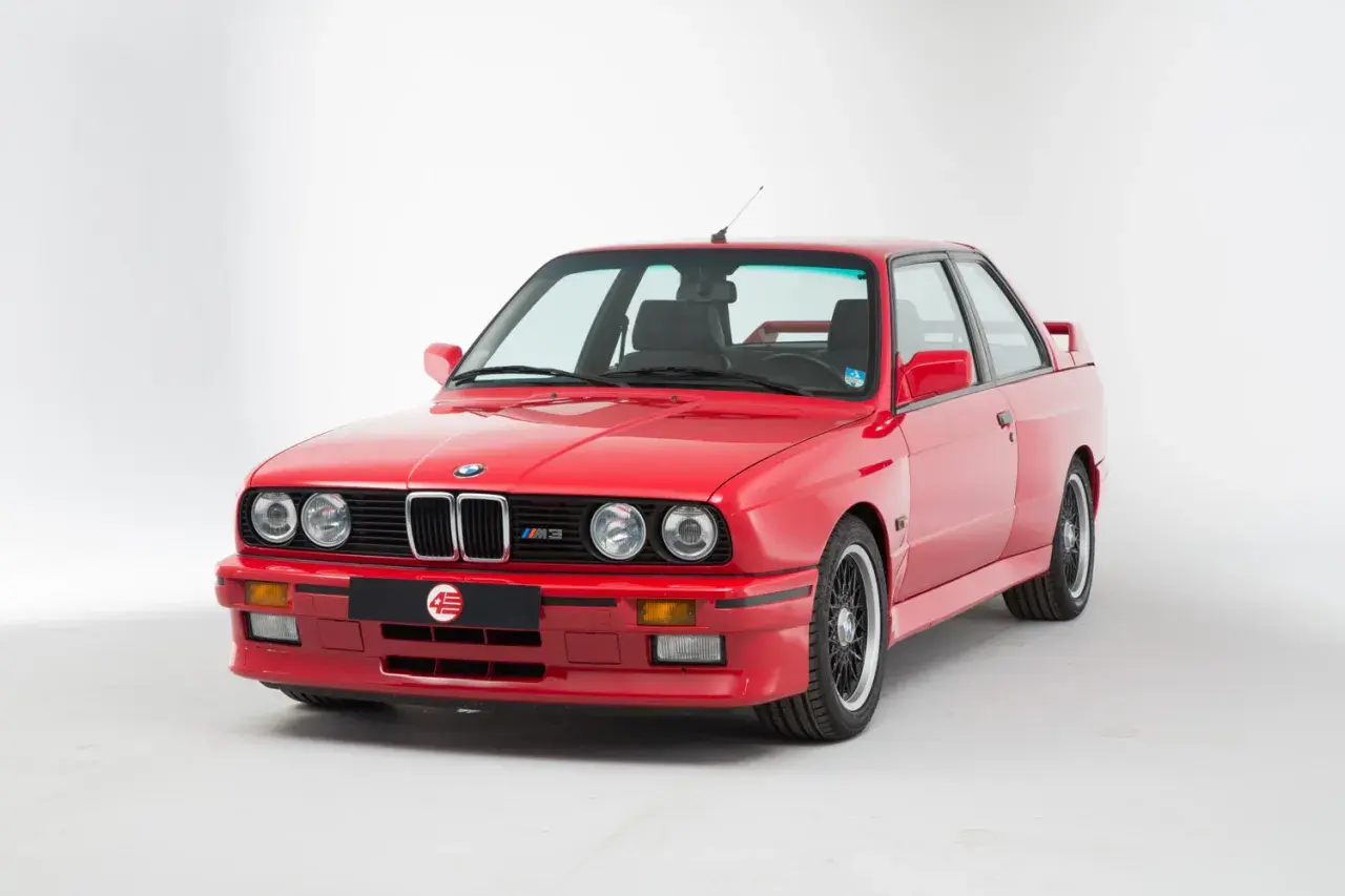 Klasyczne czerwone bmw e30 coupe z czarnymi felgami i emblematem M3. Ikona motoryzacji.