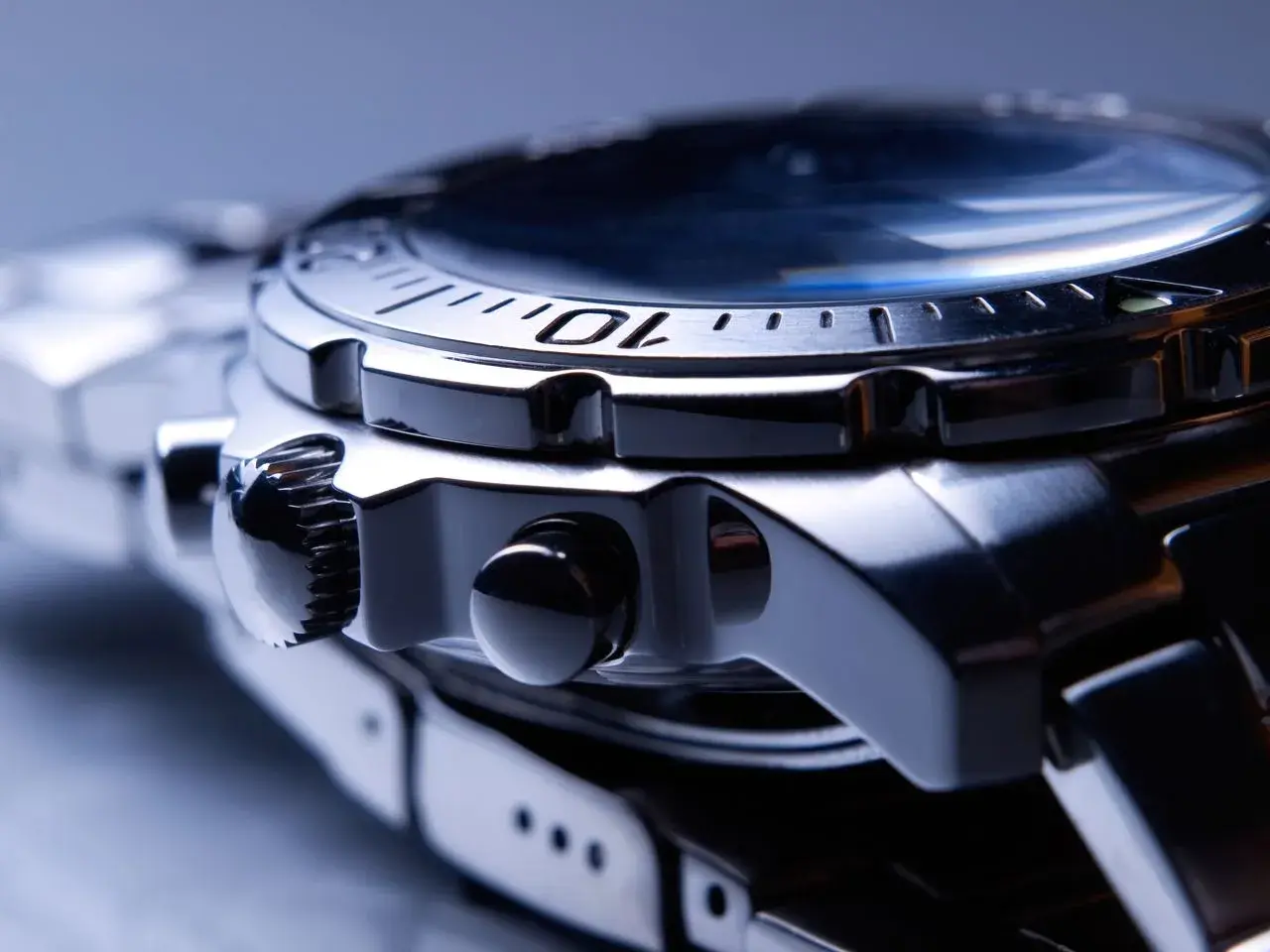 Reloj de pulsera con caja y brazalete de acero inox. Detalle de la corona y pulsadores.