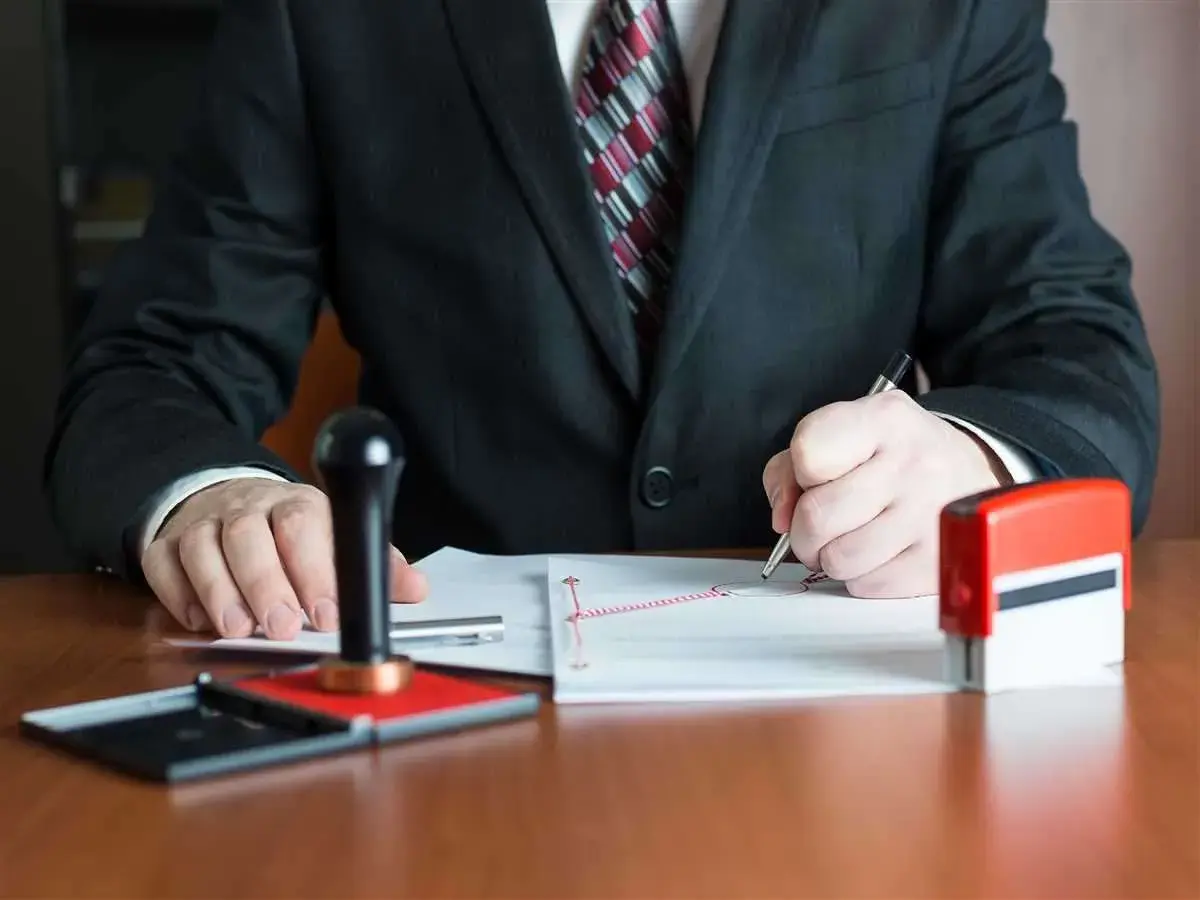 Notaio firma documenti, con timbro e inchiostro pronti per il deposito prezzo.