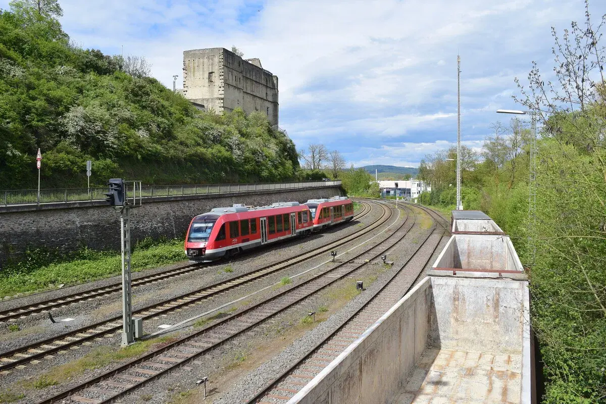 Roter Zug fährt auf Gleisen an einer Burgruine vorbei. br 640.