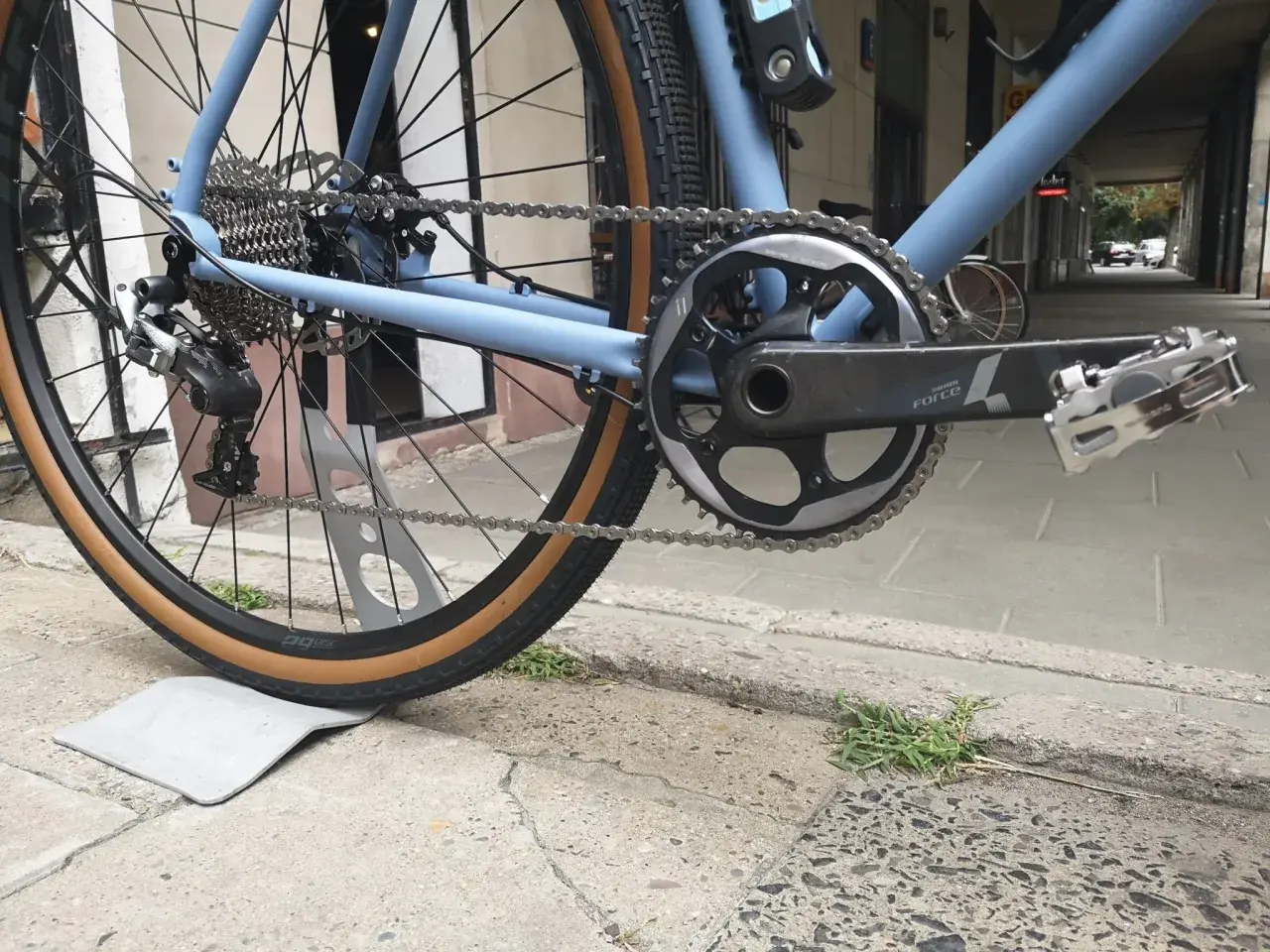 Błękitny rower z napędem Shimano, widok na tylne koło, kasetę i korbę.