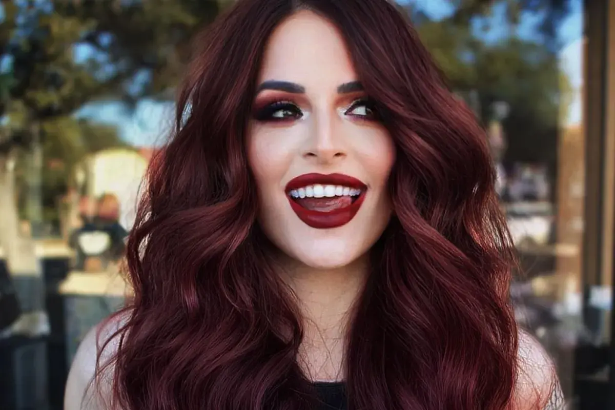 Capelli color cherry cola, labbra rosse audaci e uno sguardo malizioso.