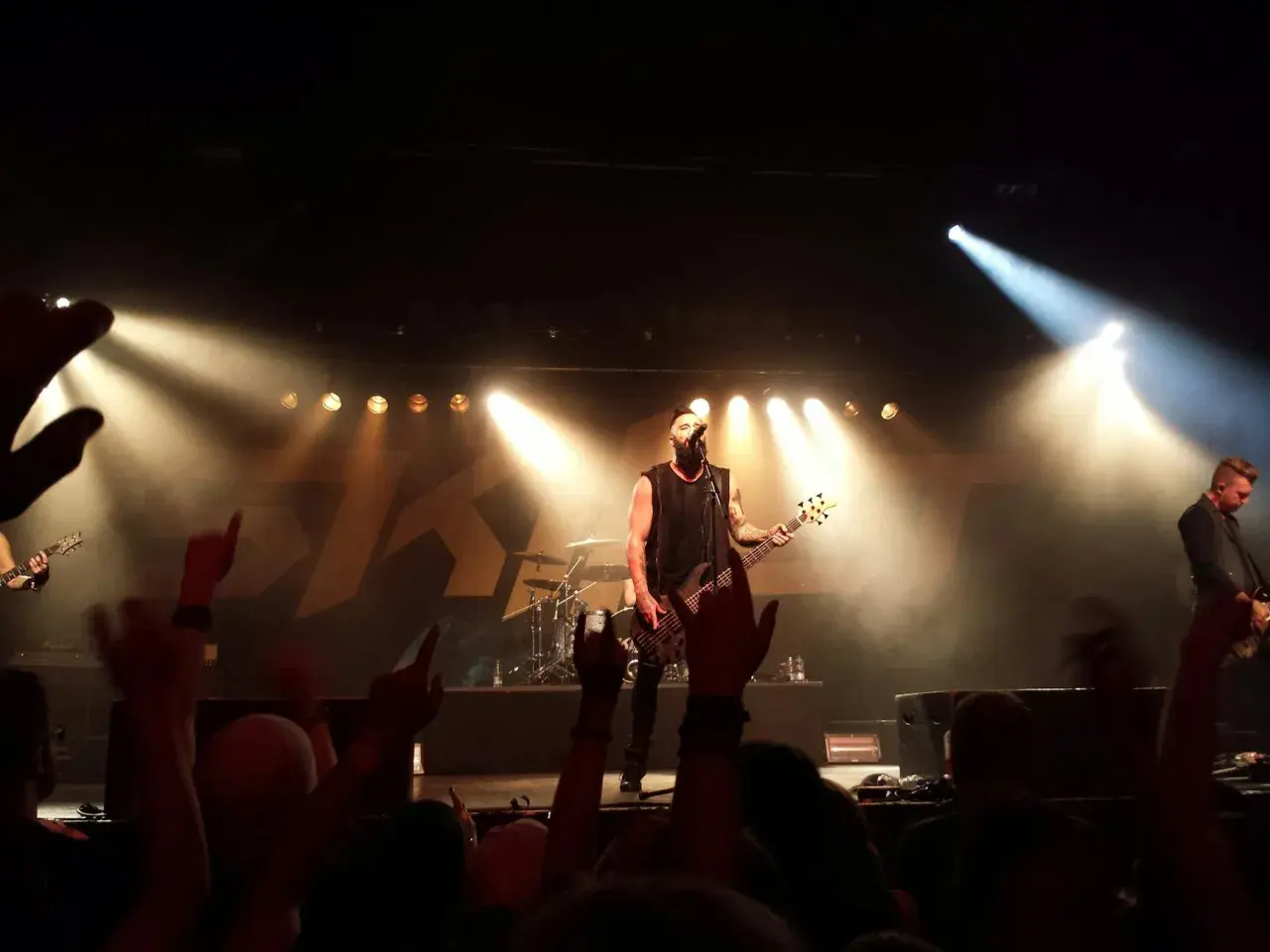 Koncert jednego z najsłynniejszych zespołów rockowych. Wokalista z basem na scenie, tłum szaleje.