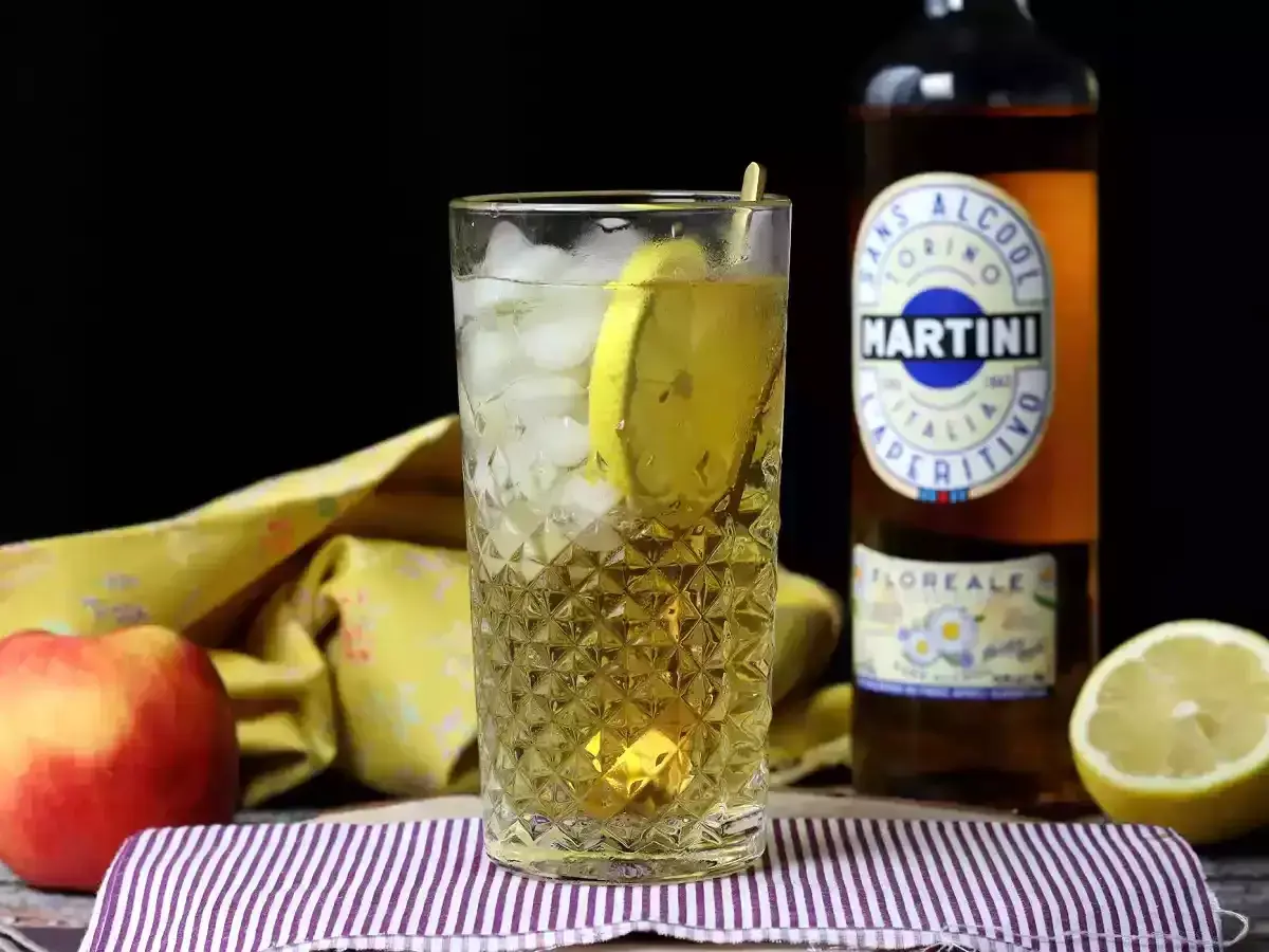 Orzeźwiający martini vibrante z lodem i cytryną, obok butelki Martini i owoców.