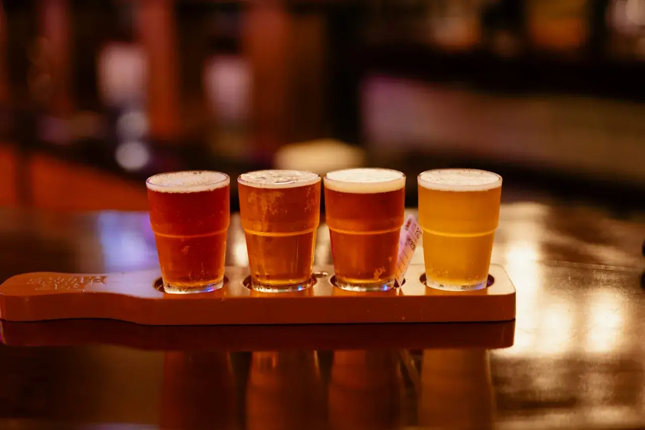 Quatre verres de bière, dont une rye IPA, sur un plateau en bois.