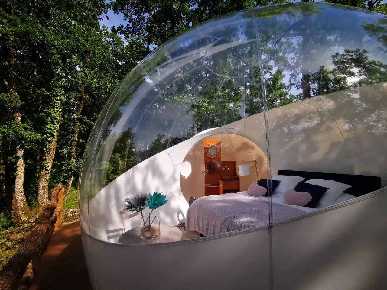 Une bulle transparente au cœur de la nature pour dormir dans une bulle Occitanie. Lit douillet, table et fleurs pour un séjour unique.