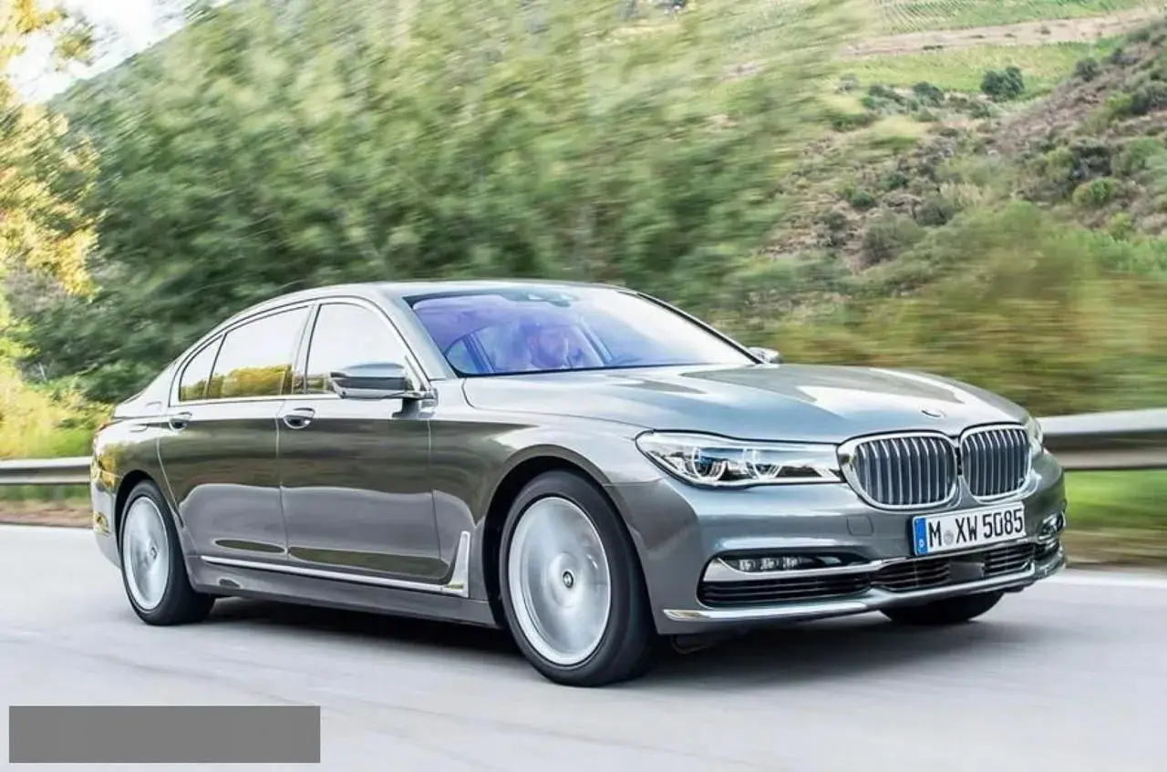 Eleganckie BMW 730d sunie po krętej drodze wśród zieleni.