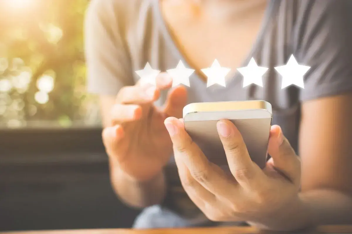 Une personne utilise son smartphone pour laisser un avis 5 étoiles, un élément clé du marketing digitale.