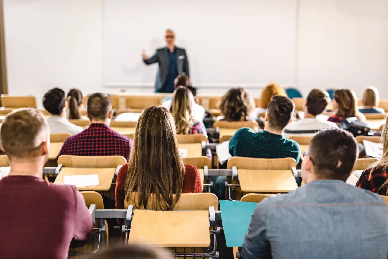 Dozent spricht vor Studenten im Hörsaal. Viele junge Leute, die vollzeit arbeiten und studieren, sind aufmerksam.
