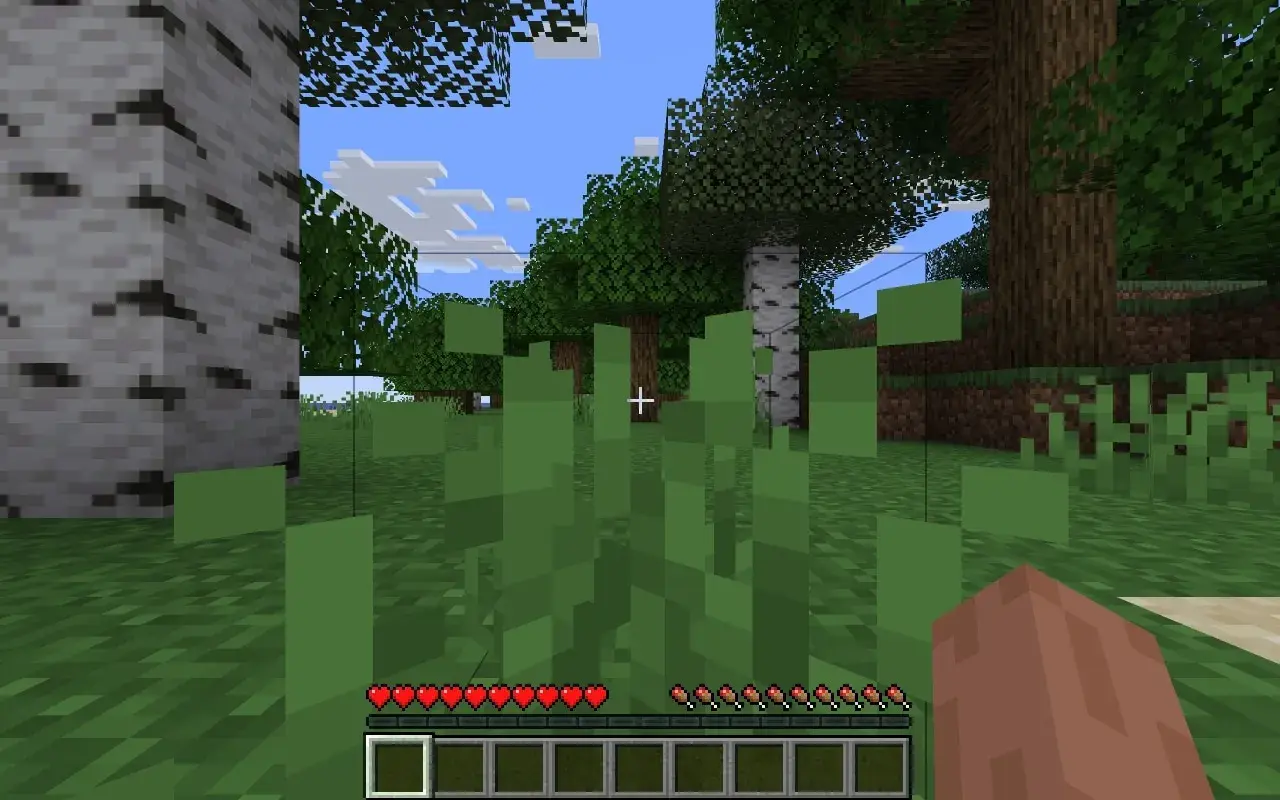 Wirtualny świat Minecraft. Gracz stoi wśród zielonych traw, widząc drzewa i niebo. Na dole ekranu pasek zdrowia i ekwipunek, gdzie widać jeden pusty slot.