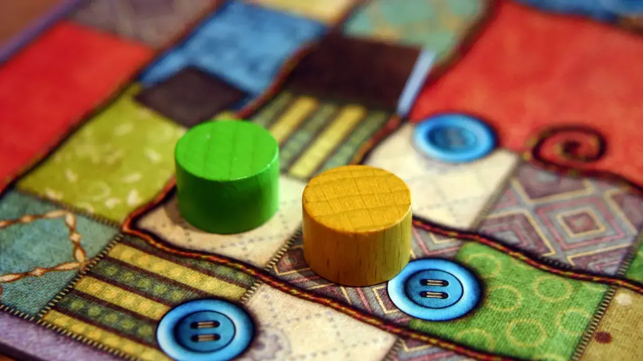 Zwei Holzfiguren auf einem bunten Brettspiel mit Knopf-Symbolen. Perfekt für die besten 2 Spieler Brettspiele.