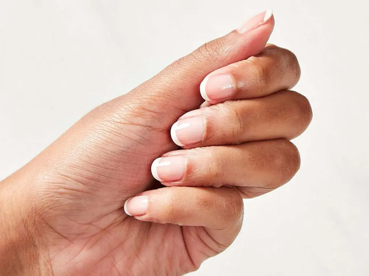 En hand med perfekt fransk manikyr och trind nagellack.