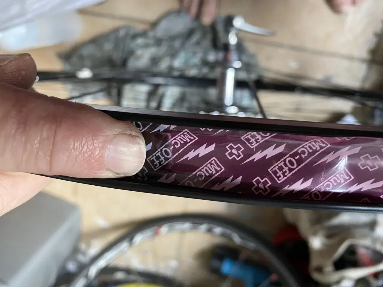 Close-up of a finger pressing down on Muc-Off tubeless rim tape, showing the process of how to tape tubeless rims for a secure seal.