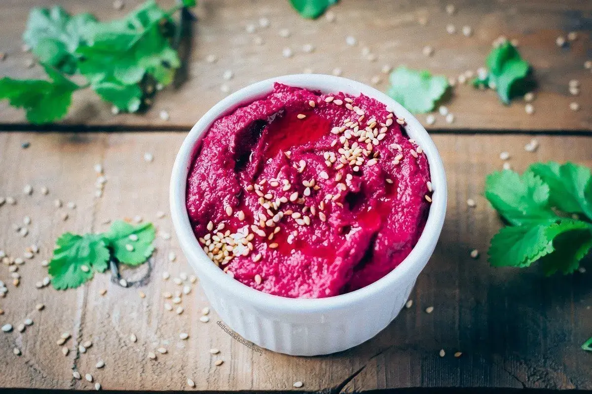 Hummus de remolacha, una de las mejores remolacha recetas, adornado con semillas de sésamo y un chorrito de aceite.